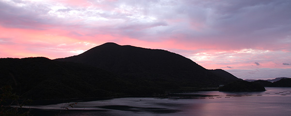 夕焼けの海と山